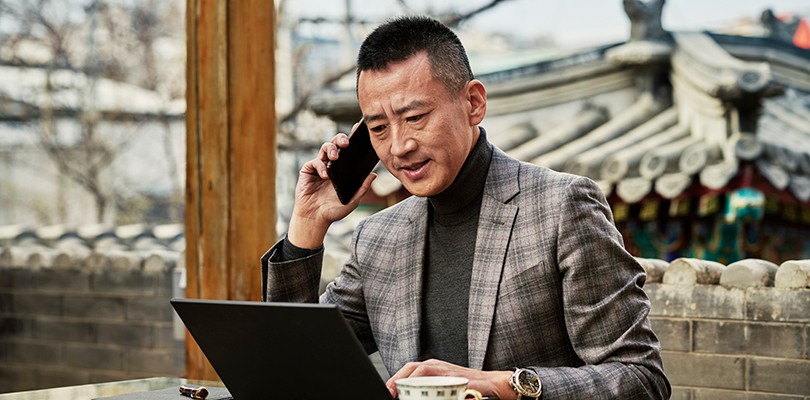 Man on the phone working outside with laptop