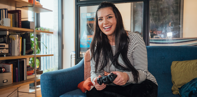 Woman sitting on couch playing video game.