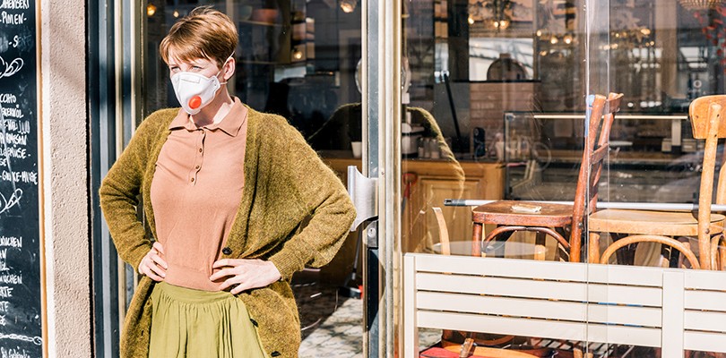 Woman wearing a facemask standing outside her café