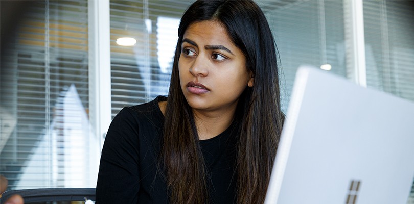 Female office worker sitting at conference room table and taking notes with pen and paper