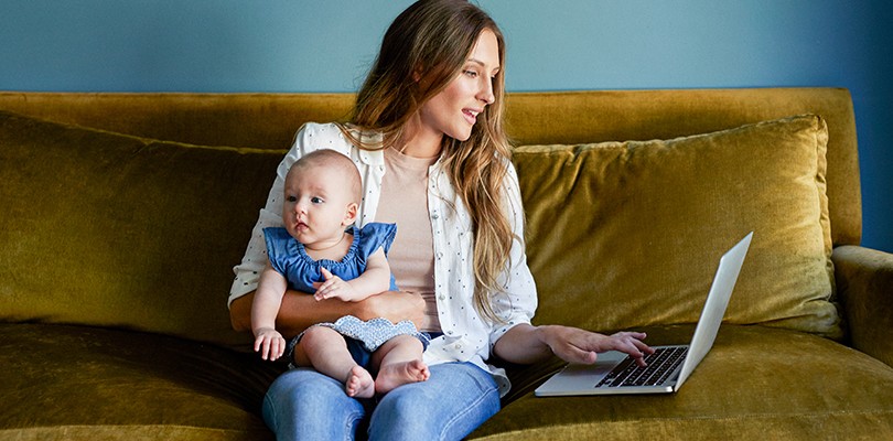 Woman working on a couch holding her baby
