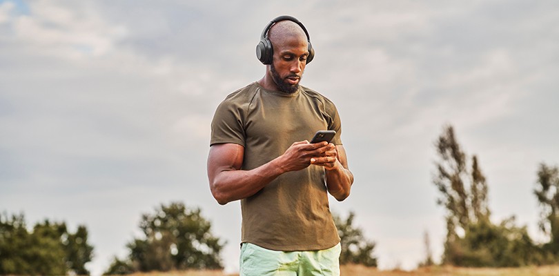 Man with headphones checking his phone outside
