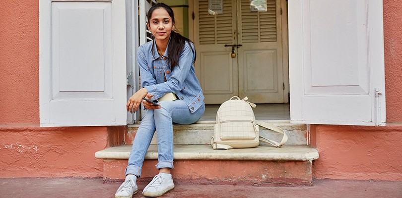 A woman sits on a step outdoors looking ahead confidently.