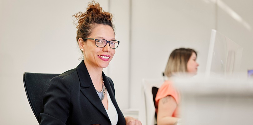 Woman with a paper sitting at desk smiling