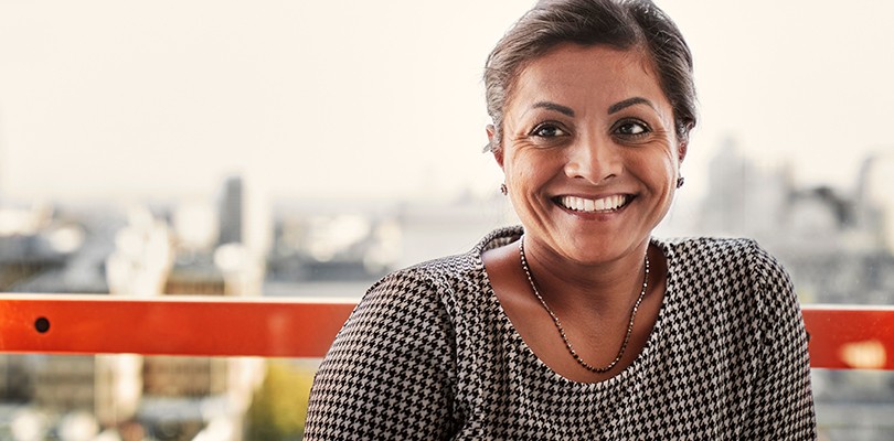Woman smiling at a peer not pictured. City skyline in the background