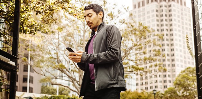 Male marketers looking at phone, walking outside