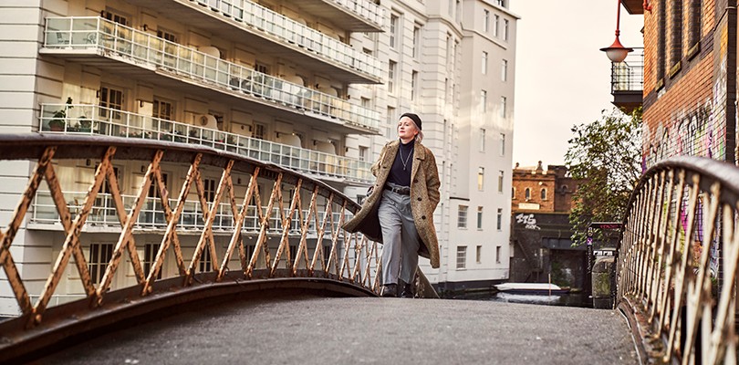 A woman walking across a bridge through the city.