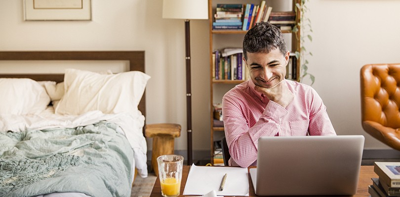 Happy man watching video on laptop at home