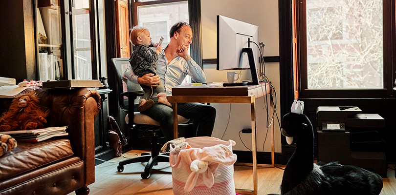 Man holding a baby while working from home