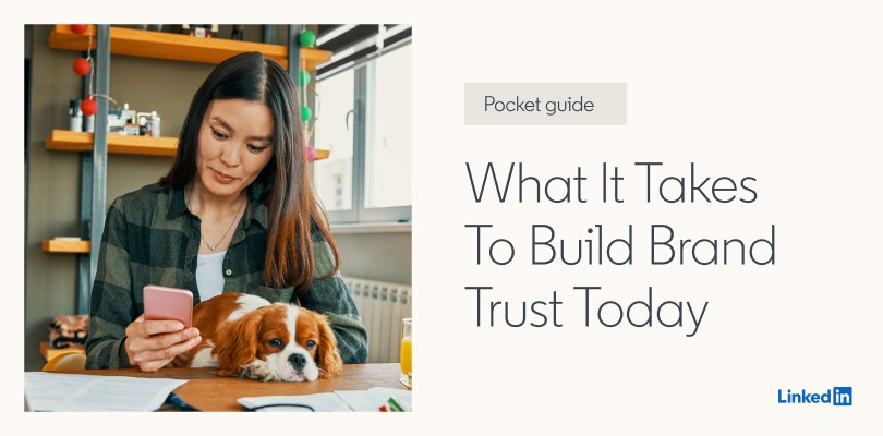 Woman holding dog in lap, looking at smartphone.