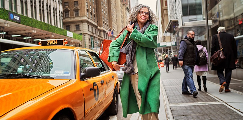Woman adjusting her bags as she walks down the street in a city