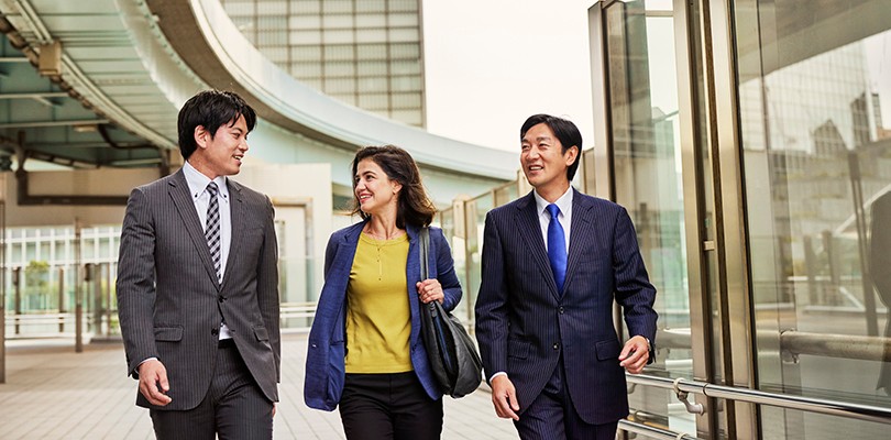 Two men and a woman walking and talking outside