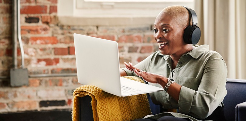 Woman with headphones laughing at laptop