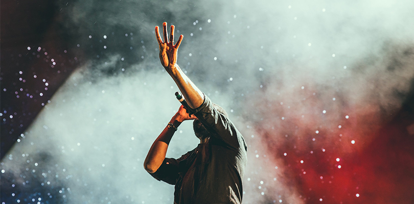 A Singer on Stage Extends His Hand to the Sky