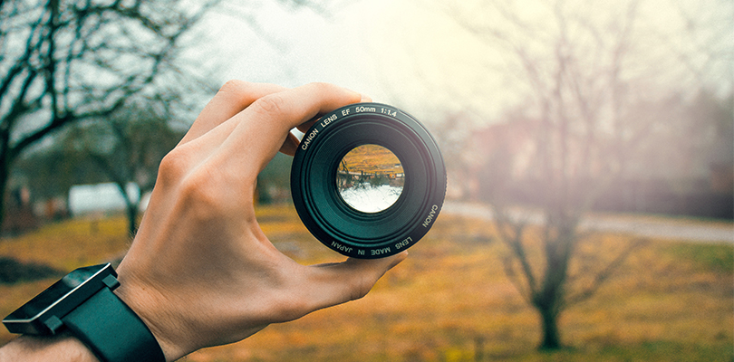 Man holds up a camera lens