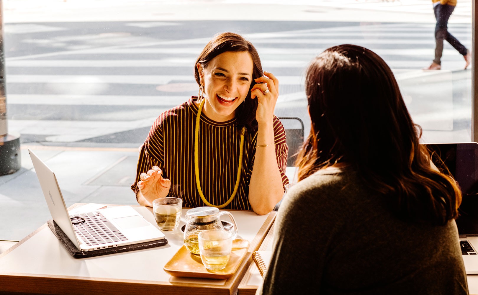 Photo of two women meeting at a table with open laptop and cups of tea