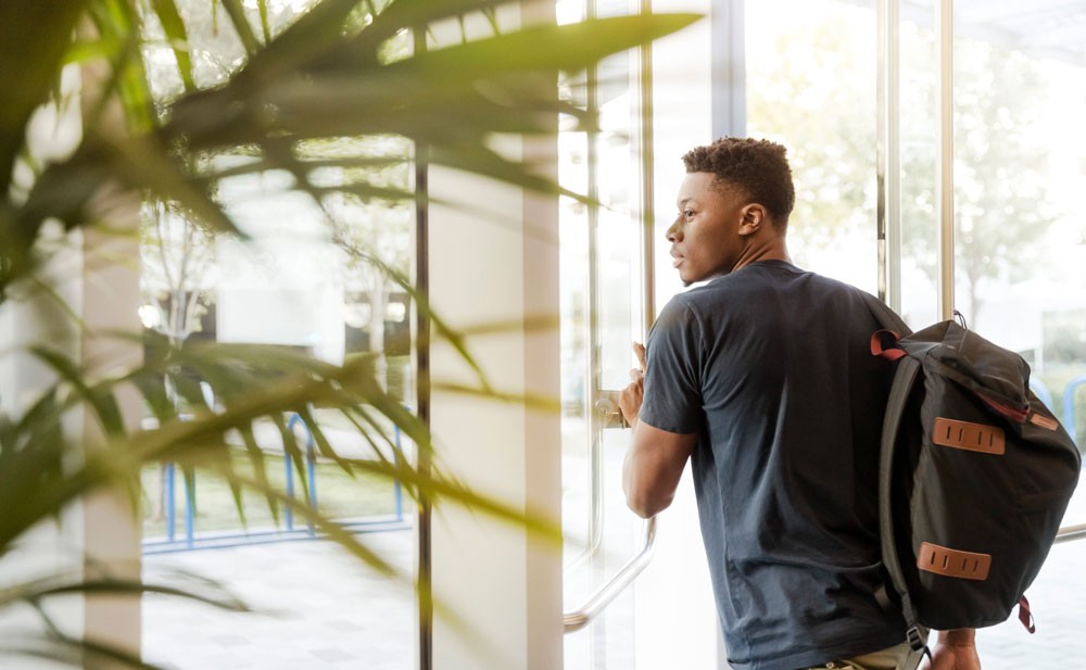 Photo of man leaving a building with his backpack