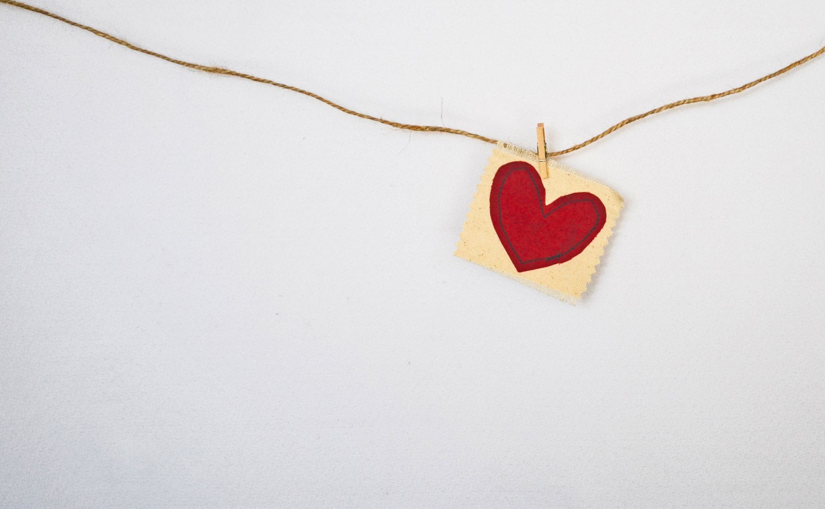 Photo of hand-drawn red heart handing from a piece of string