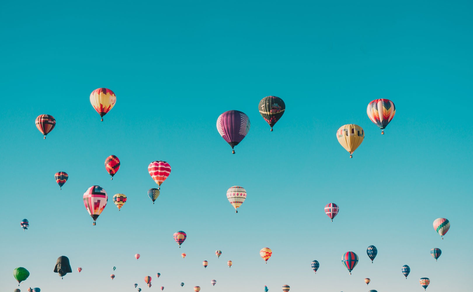 Photograph of colorful air balloons in a blue sky