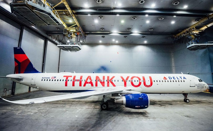 Photo of Delta airplane in hangar. The words "Thank You" are written in large letters across entire plane.