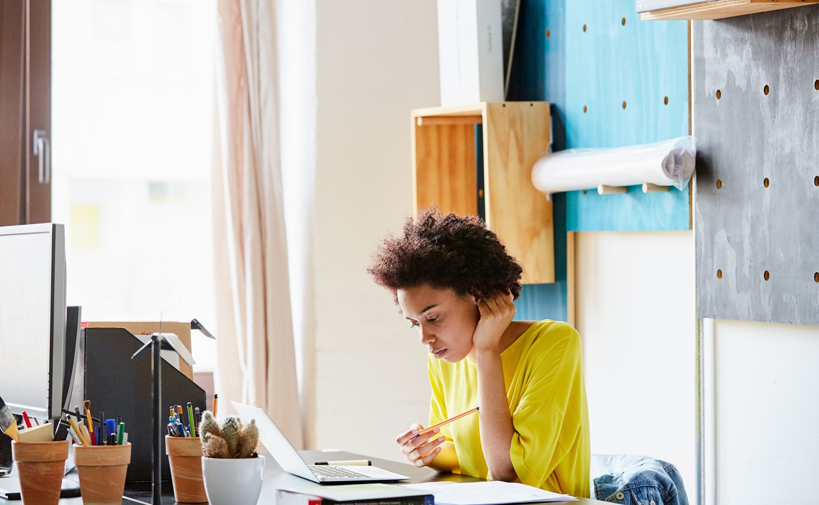 Photo of woman reading at desk with laptop