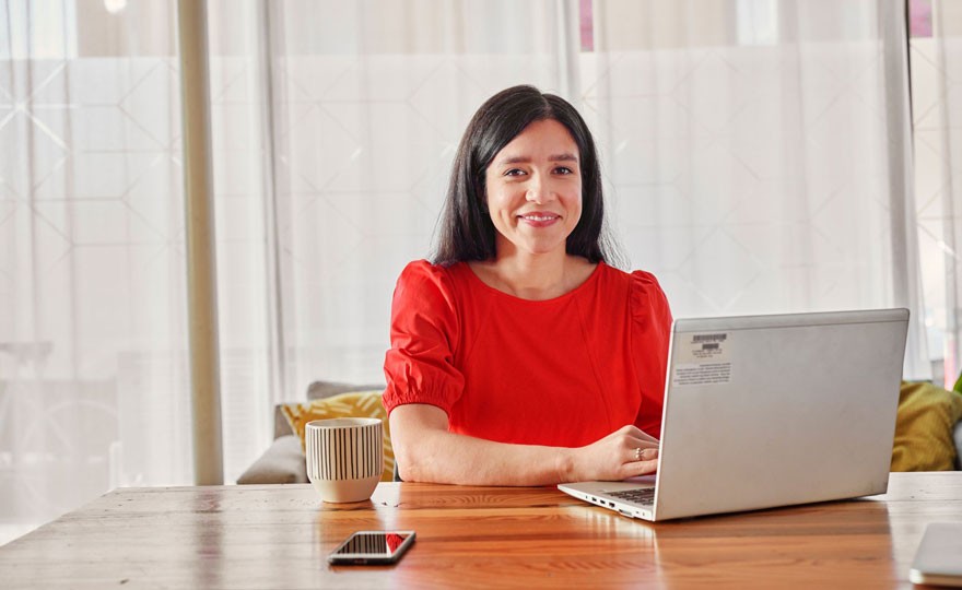 Photo of smiling woman sitting at desk with laptop