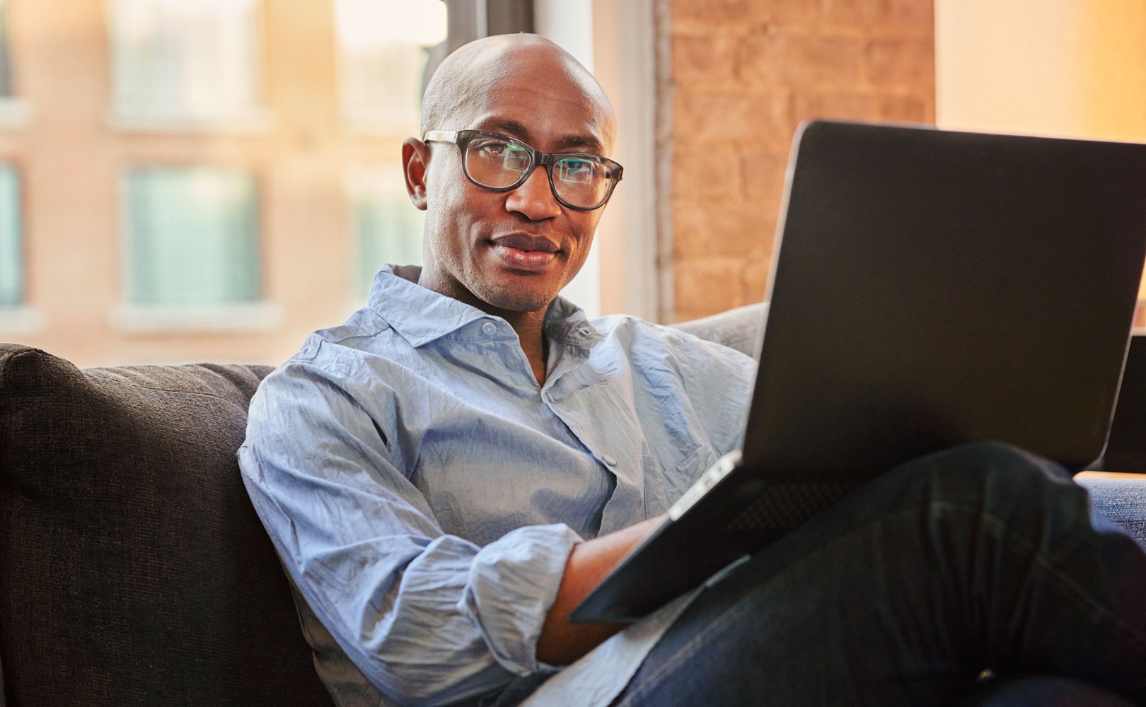 Photo of man sitting on couch with laptop