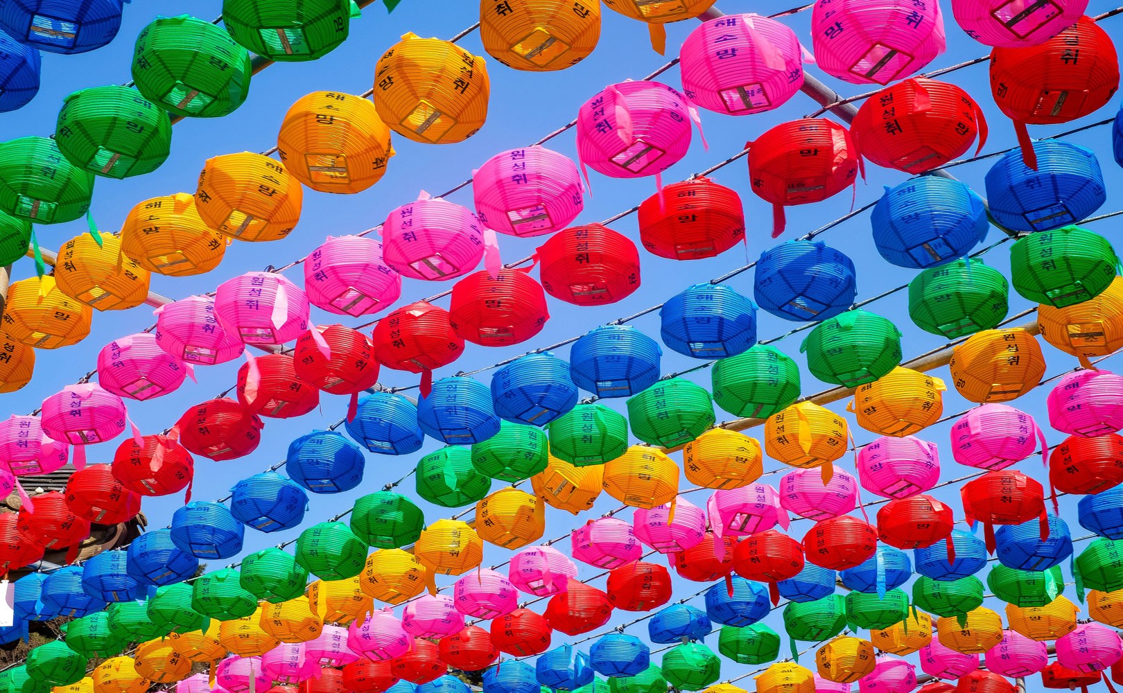 Photograph of colorful paper lanterns arranged and hung to look like Pride flag