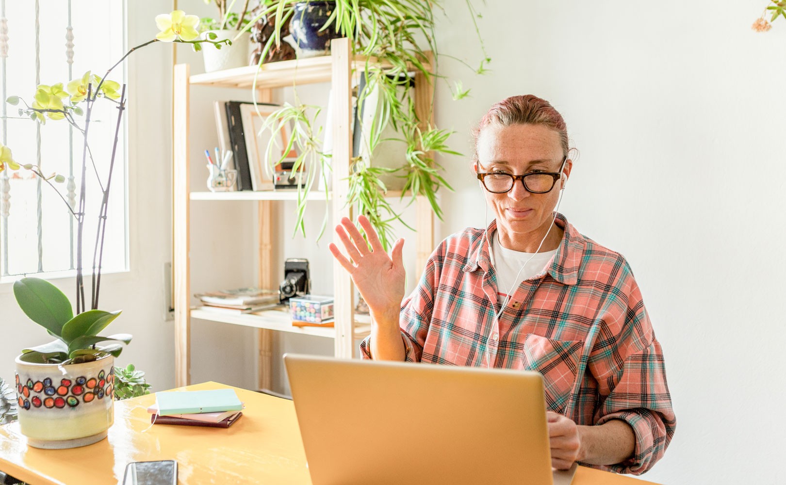 Photo of woman working from home while on video call with headphones