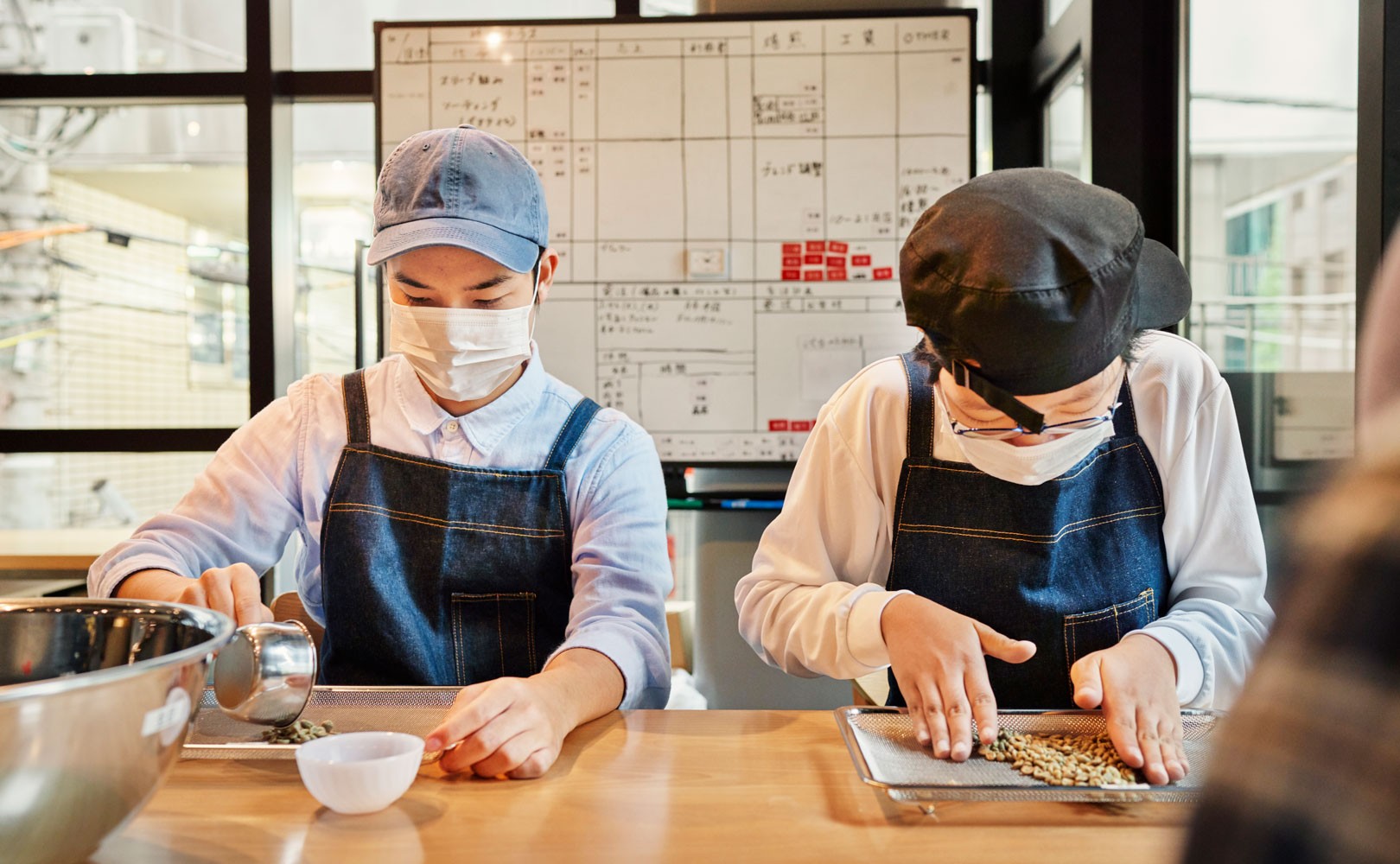 Photograph of two workers wearing facing masks in kitchen