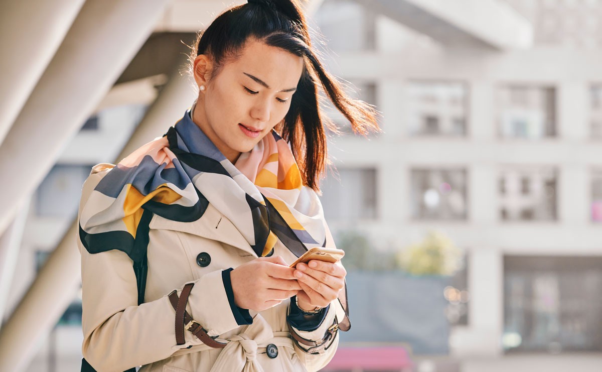 Woman standing outside looking at her phone