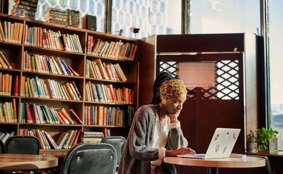 Woman sitting at a table in a library looking at her computer