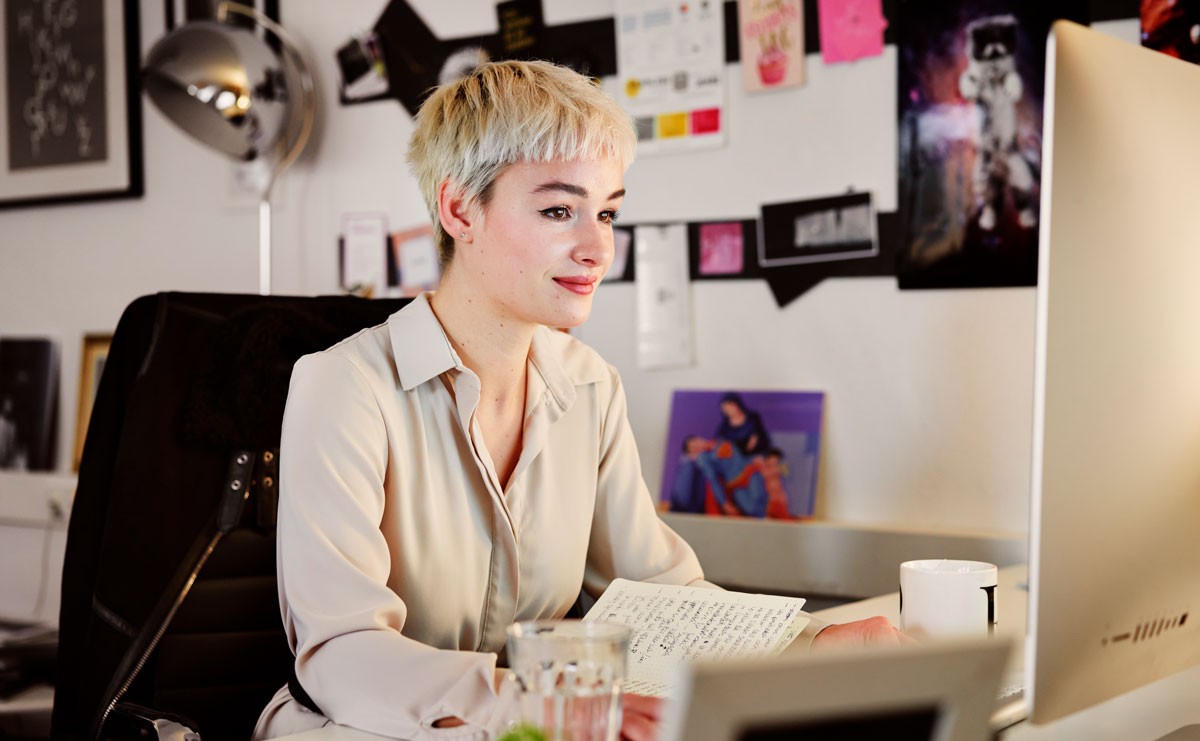 Young woman sitting at desk looking at her computer