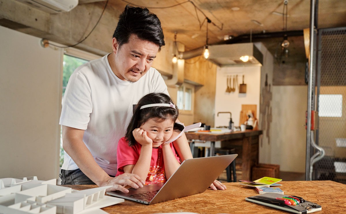 Photo of father and daughter looking at laptop screen
