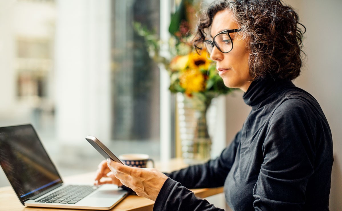 Photo of woman working on phone and laptop