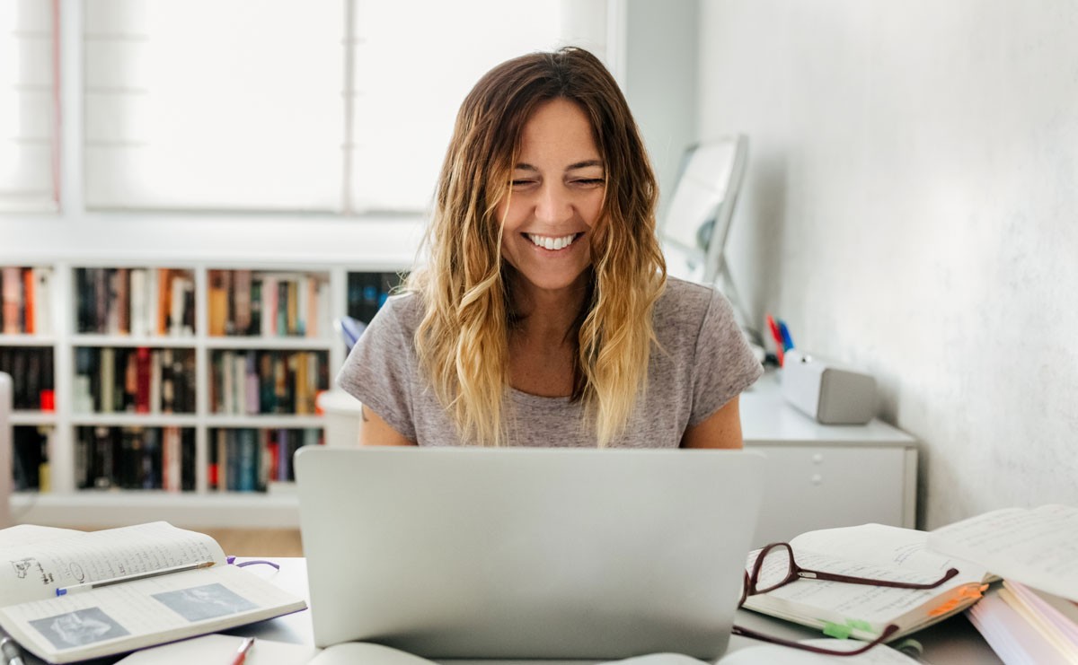 Photo of woman smiling and talking at her laptop while working from home