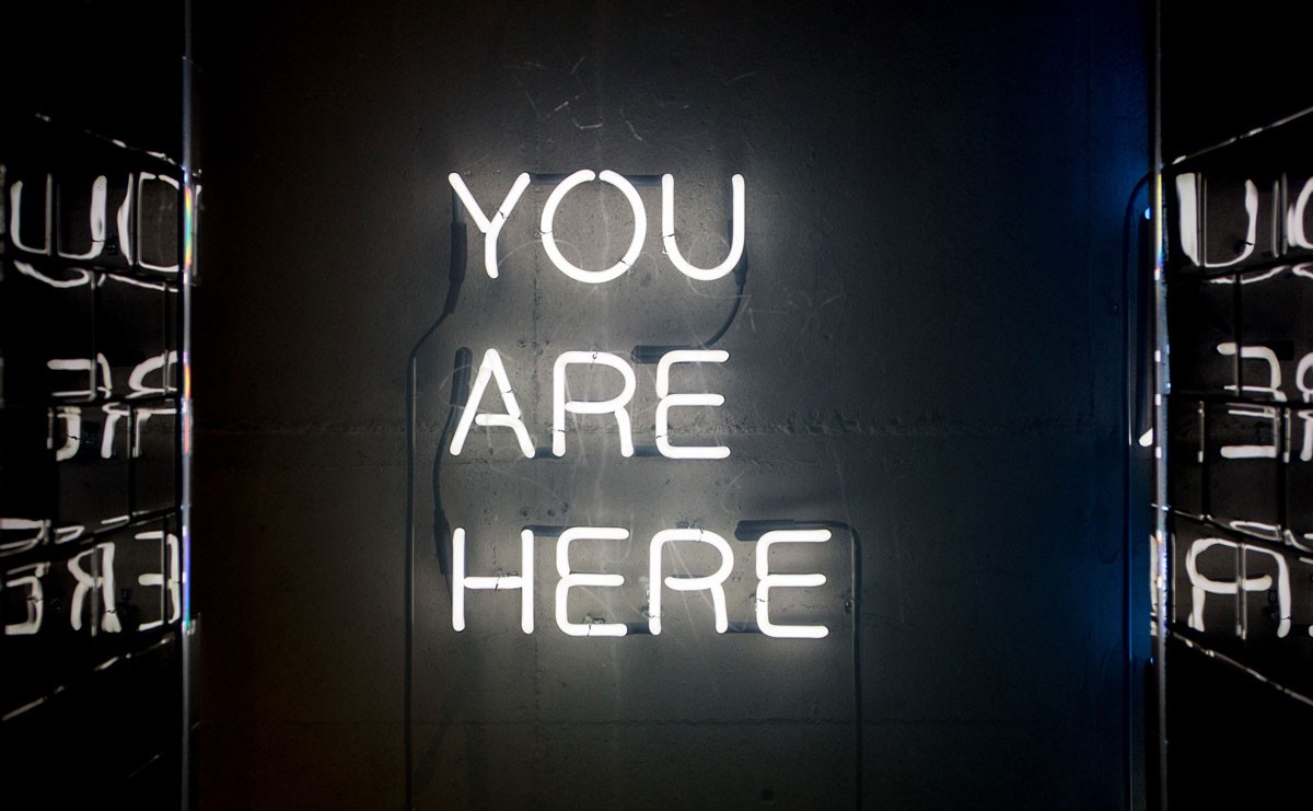 Photo of neon sign that reads "You Are Here"