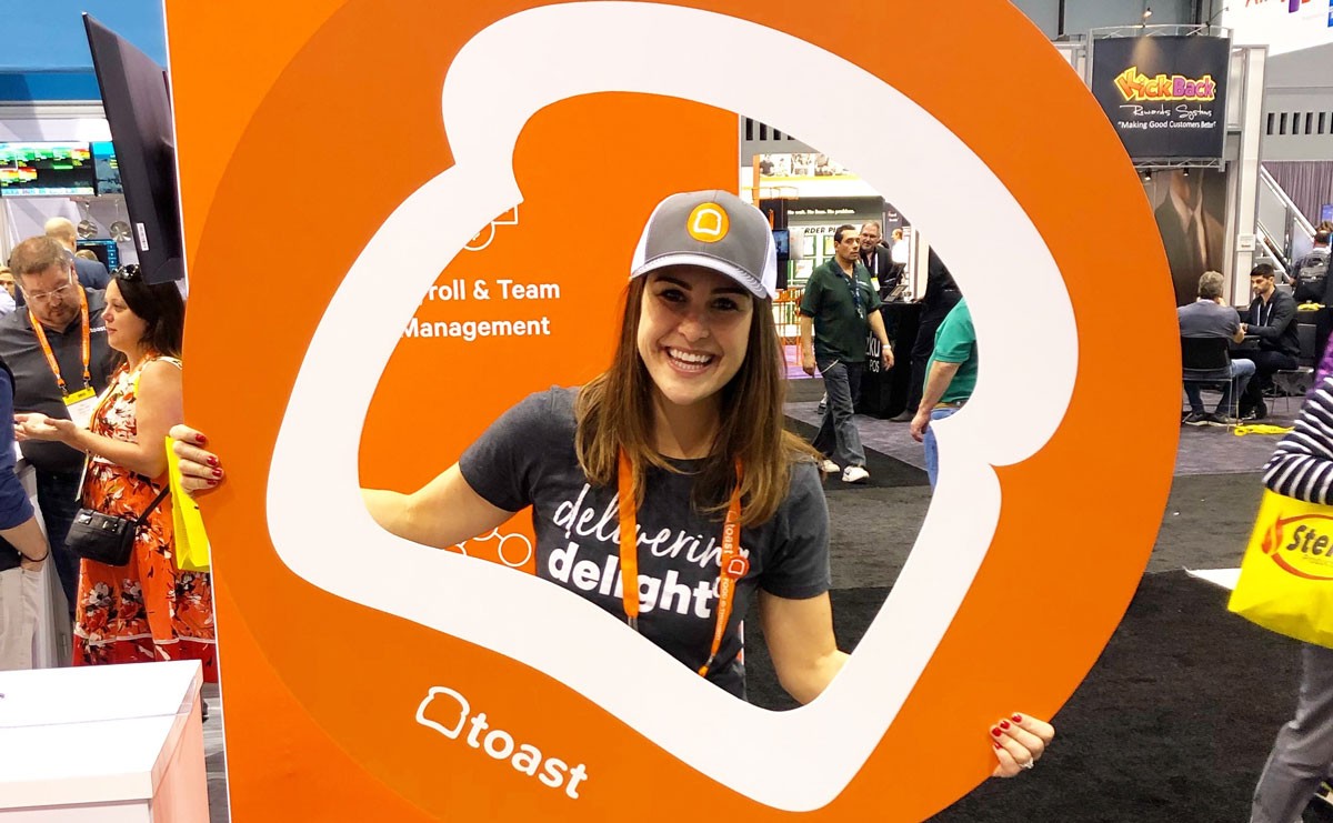 Photo of Toast employee looking through a cardboard cutout in the shape of a piece of toast