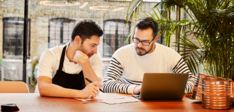 two professionals studying while using a laptop