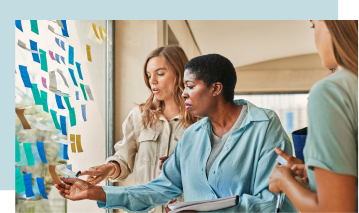 Three individuals having a brainstorming session next to a window.