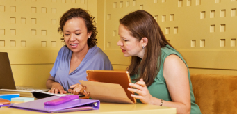 Illustration of two individuals working together at a table.