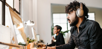 Two people working at their computer at their work station.
