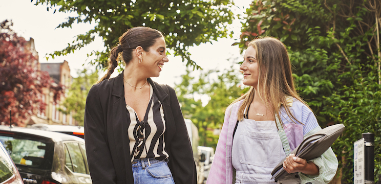 Two women facing each other and walking together outside
