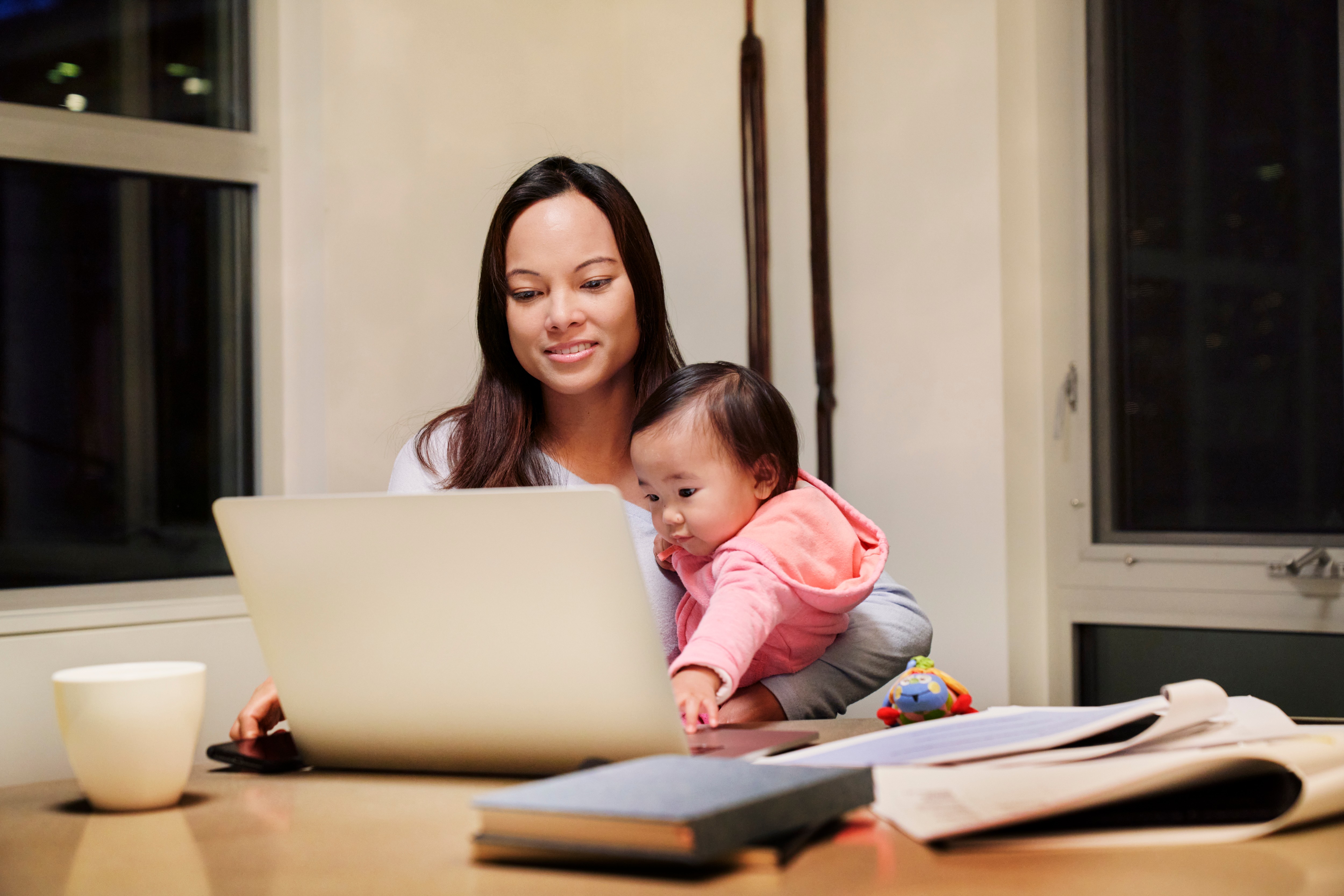 professional woman working remotely while holding a child