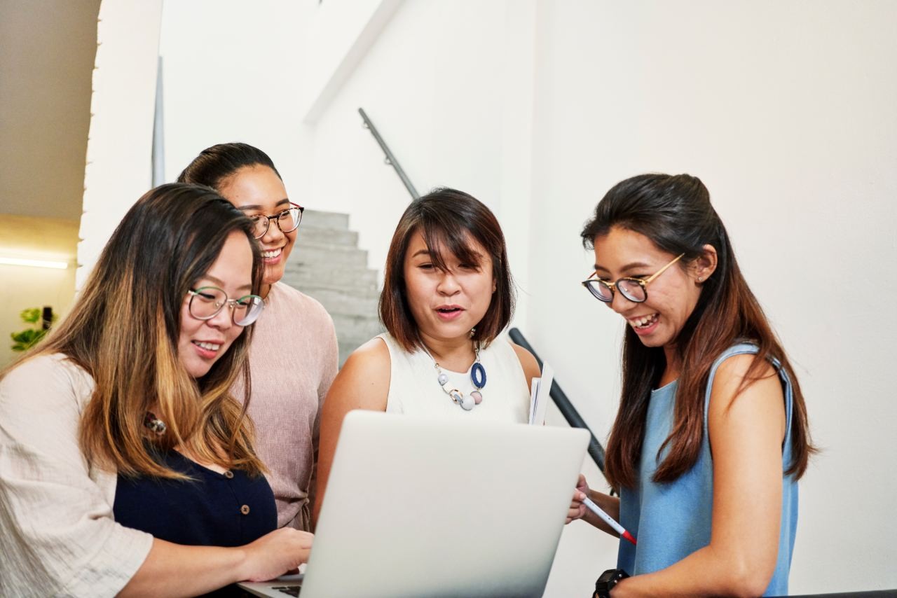 four women looking at a laptop