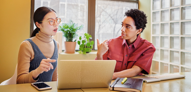 Two people having a thoughtful conversation with a laptop between them.